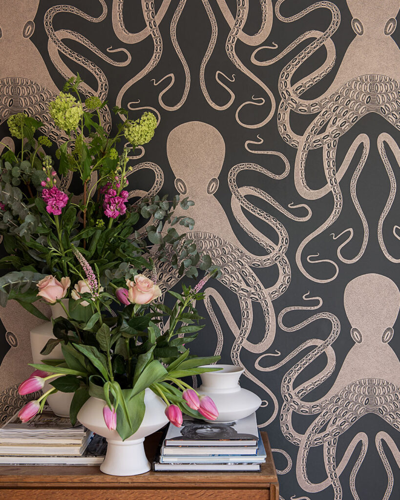 a room with black wallpaper featuring large octopuses and fresh flowers in a vase