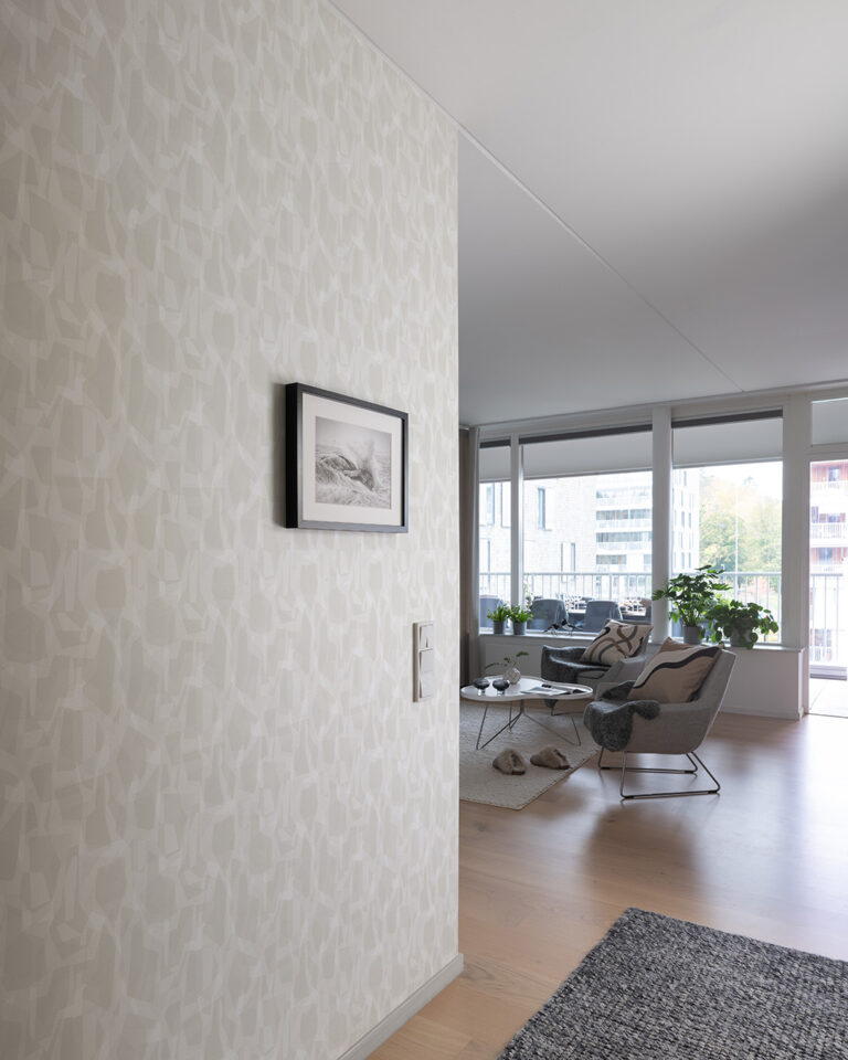 Light-colored camouflage wallpaper in a hallway adjacent to a living room with hardwood floors