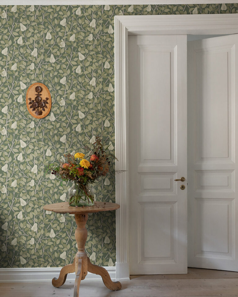 Green wallpaper with pears in a hallway with a large white door