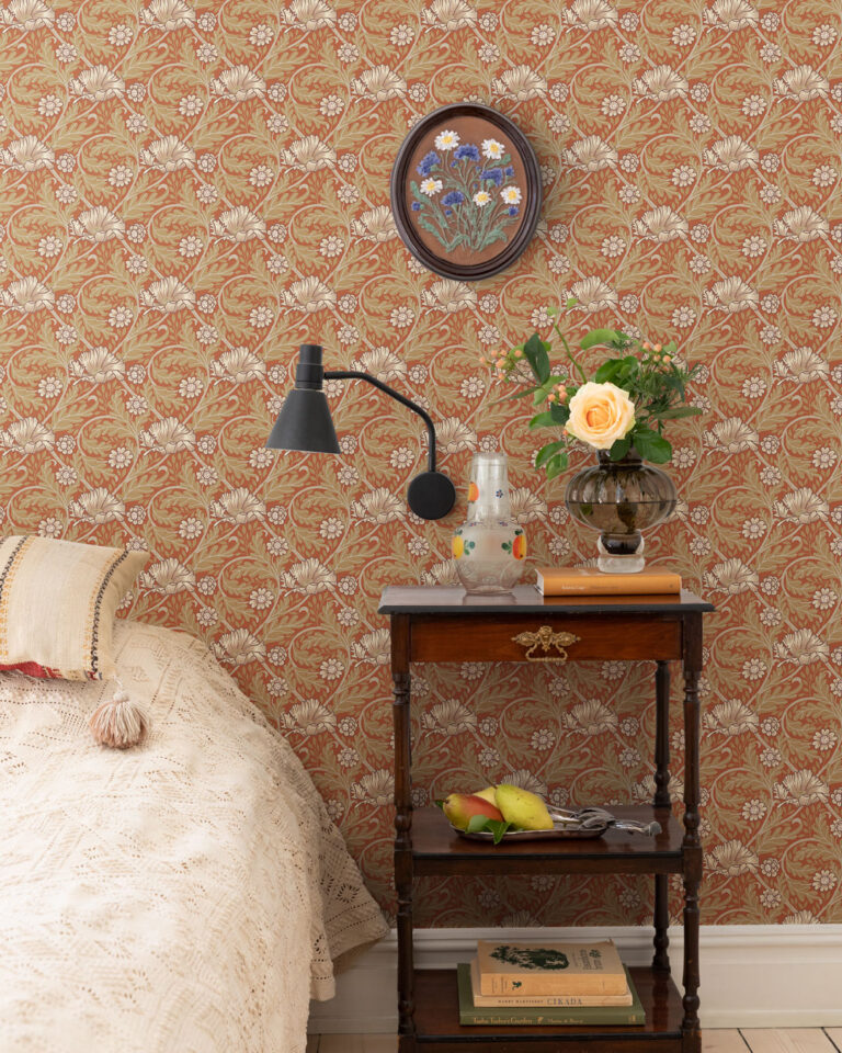 Red floral wallpaper in a bedroom with a made bed