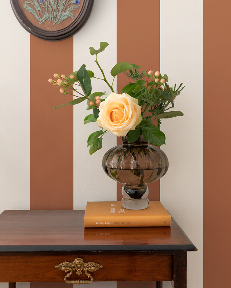 White-and-red-striped wallpaper in a hallway with a vase of flowers