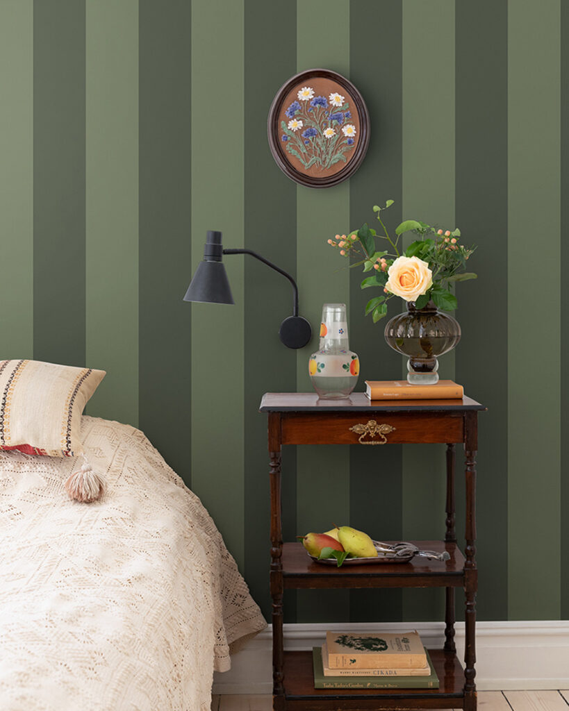 Grön randig tapet i ett sovrum med en bäddad säng