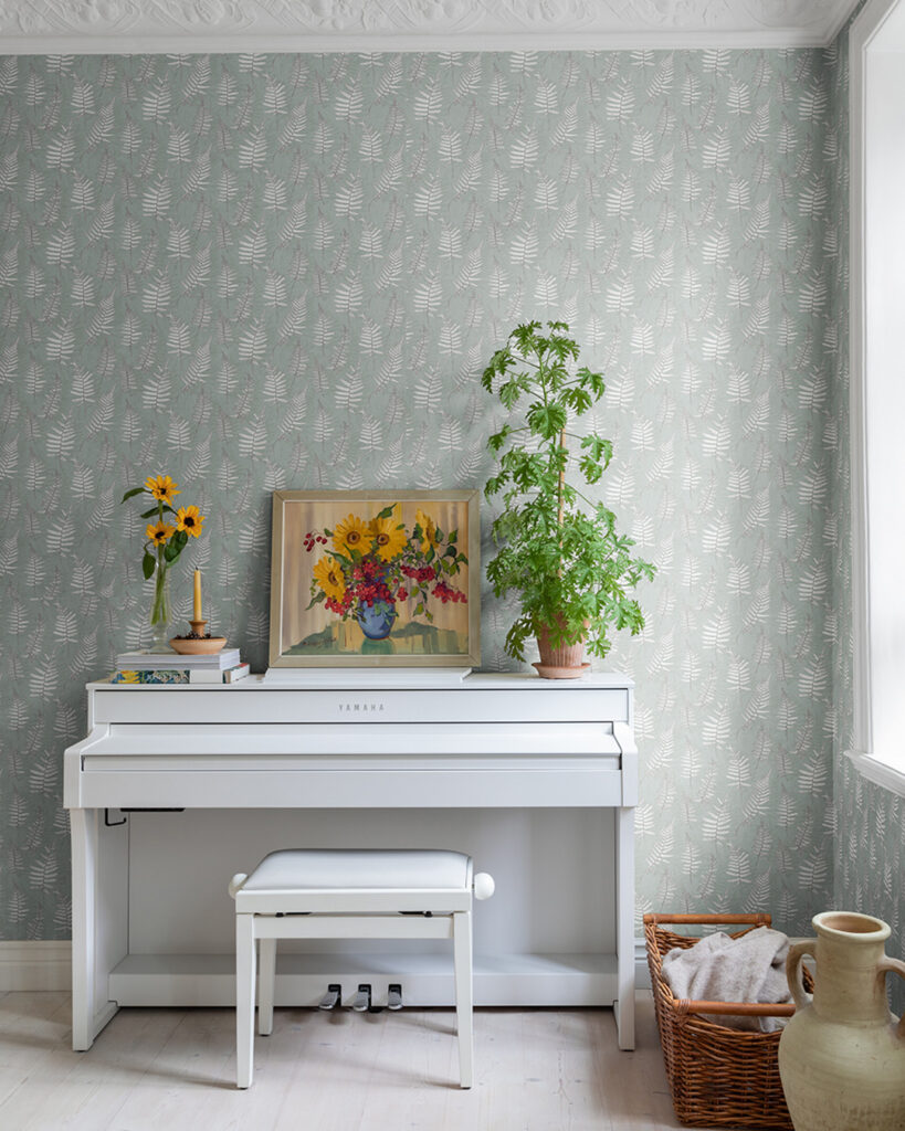 Green wallpaper with light-colored leaves in a hallway with a piano