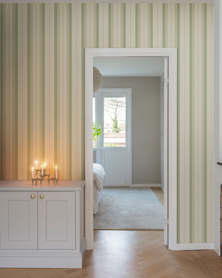 Wallpaper with varying stripes in green and warm white in a hallway