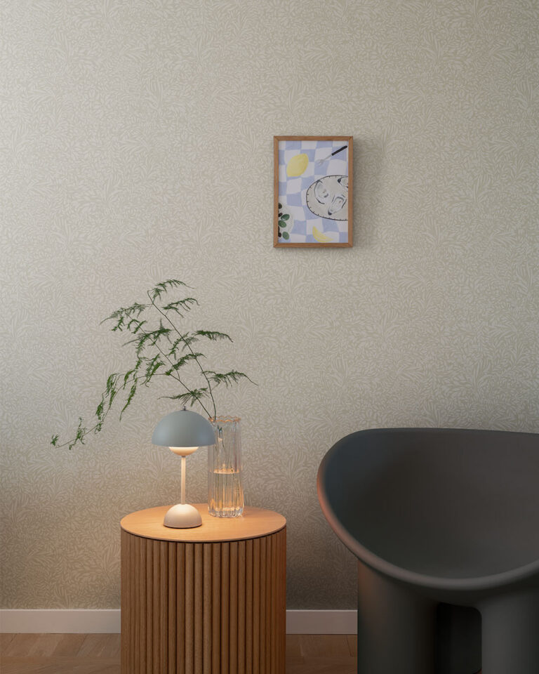 Wallpaper with a dense pattern of small beige leaves in a living room with a black armchair
