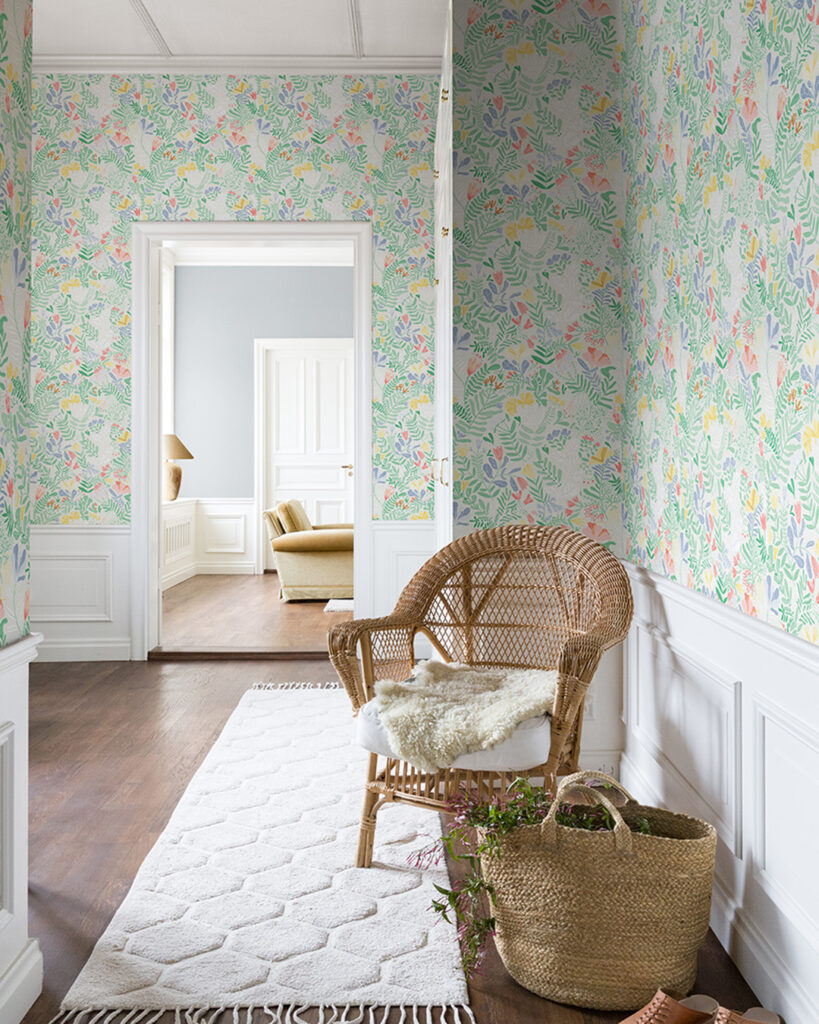 Färgglad tapet med blommor och blad i en hall med höga vita golvlister