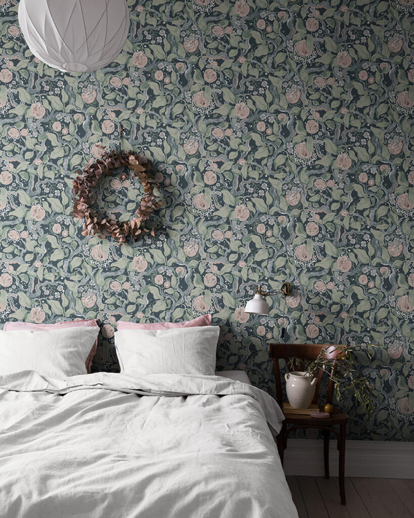 Mörk sovrumstapet med gröna blad och rosa blommor bakom en säng