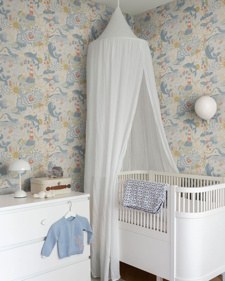 Blue, colorful wallpaper with a seaside motif and suns in a child's room with a crib