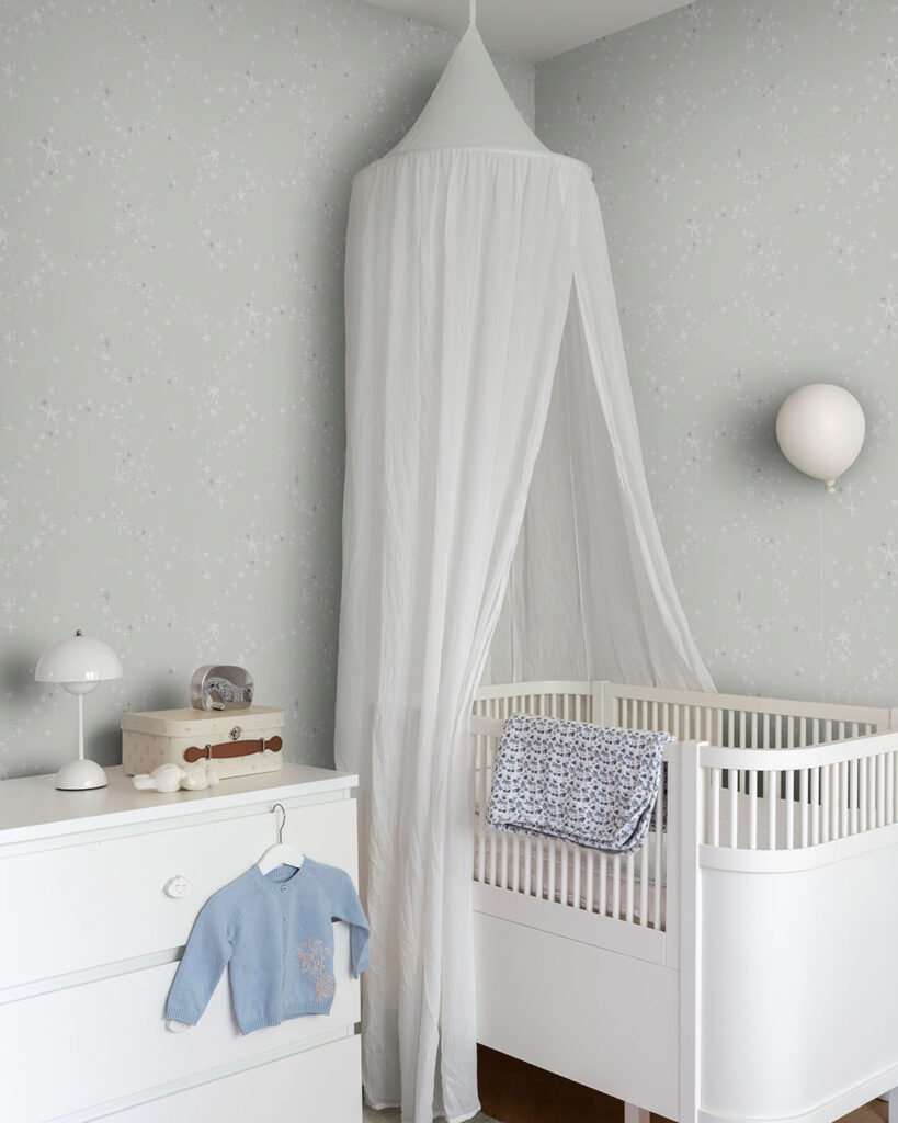 Gray wallpaper with stars in a child's room with a crib