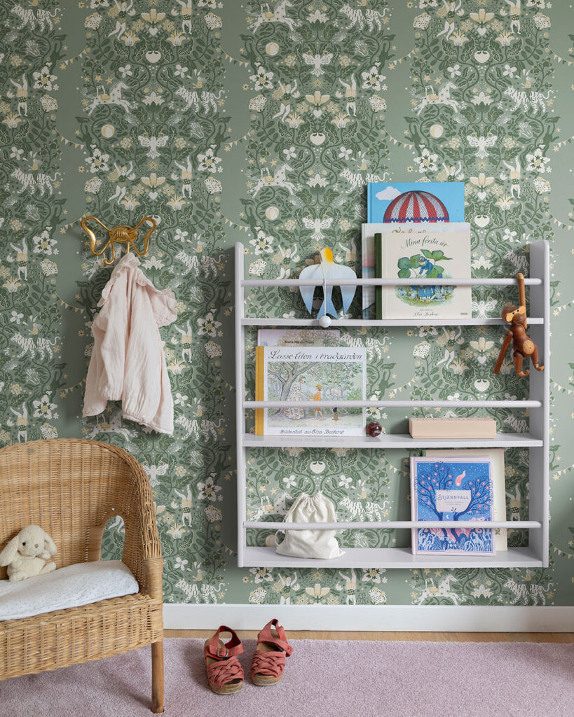 grön tapet med blommor och cirkusmotiv i ett barnrum med en bokhylla