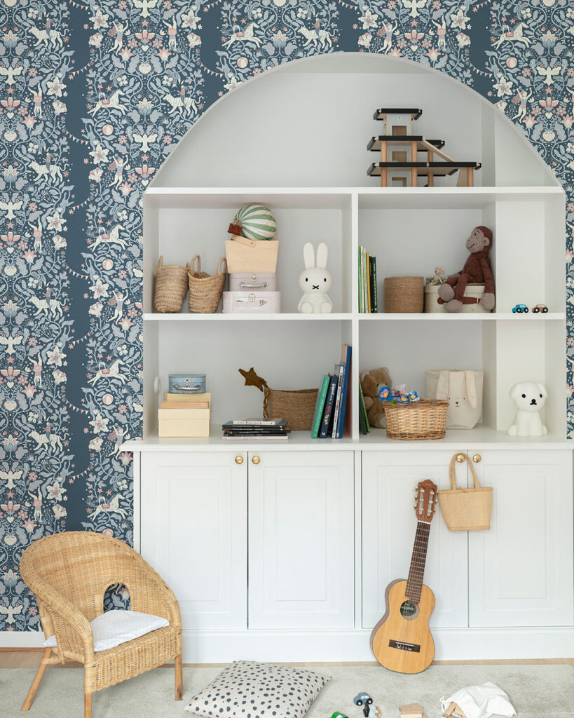 Blue wallpaper with flowers and circus motifs in a child's room with a built-in bookshelf