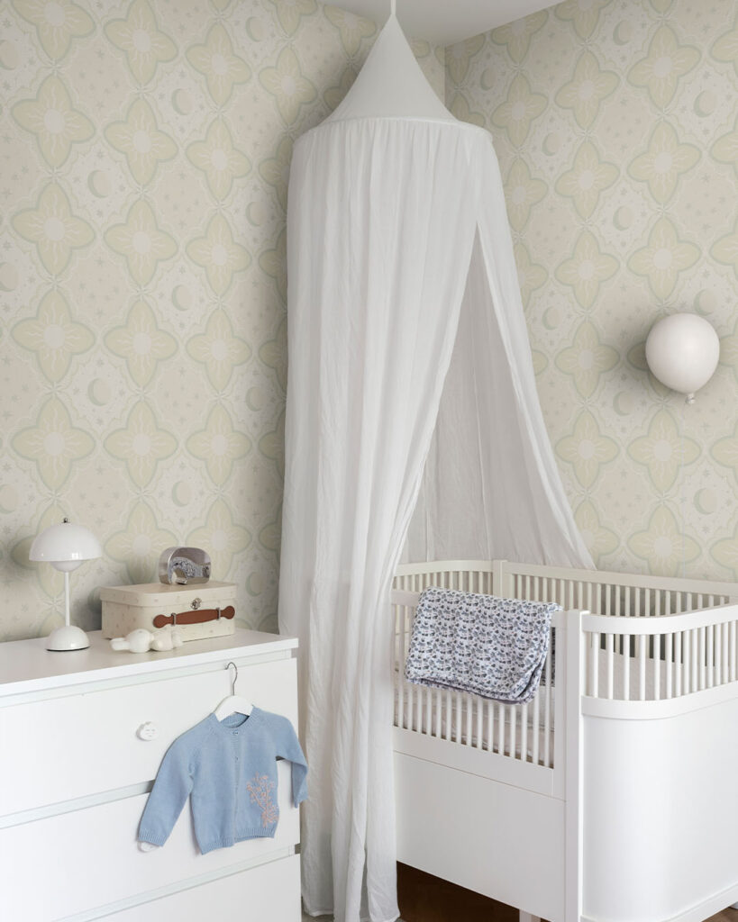 Yellow wallpaper featuring the sun and moon in a child's room with a crib and a dresser