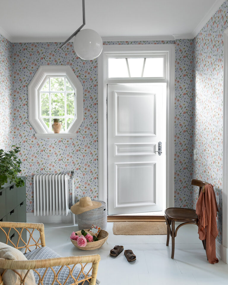 Wallpaper with a blue-gray background and flowers and leaves in various colors in a rustic hallway