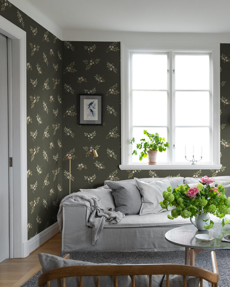 Wallpaper with a dark green background and flowers in a living room with a gray sofa