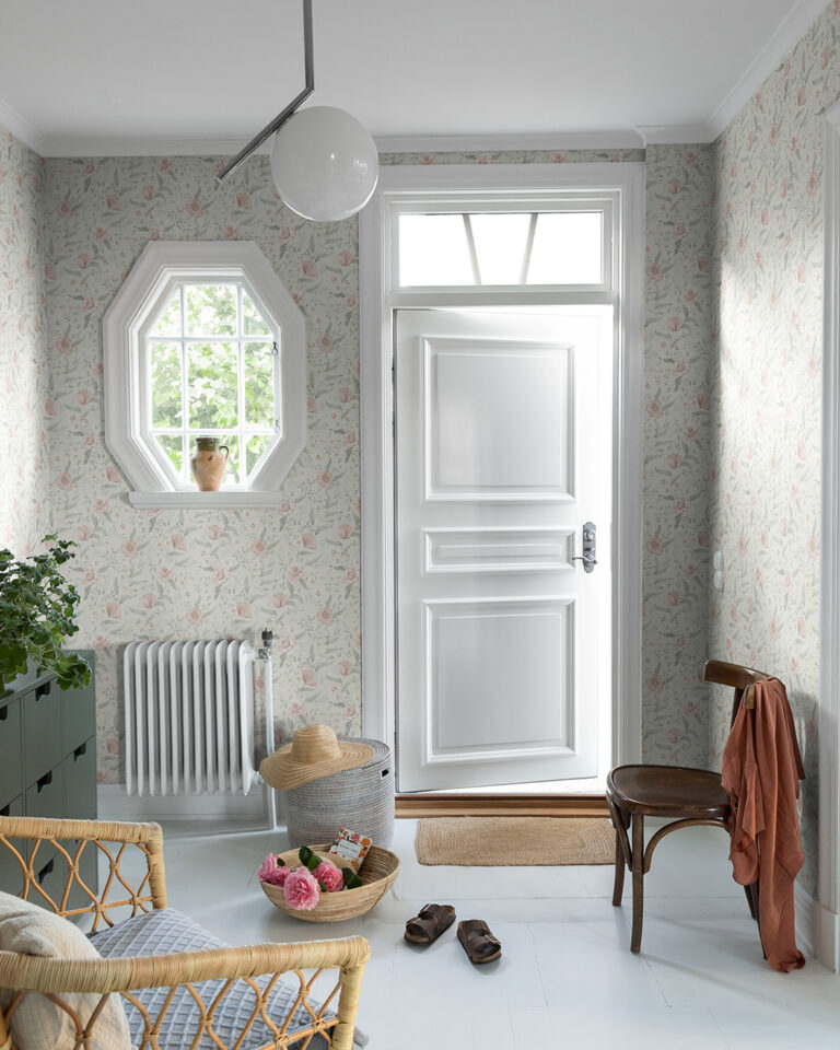 Floral wallpaper with a light blue background in a hallway with chairs and plants