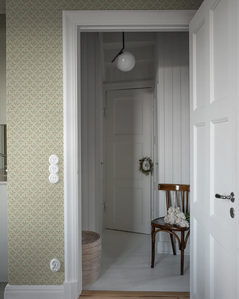 A rustic wallpaper with a beige background featuring small strawberry plants on a wall with white floors and door moldings