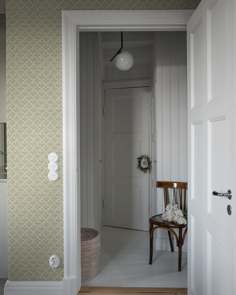 A rustic wallpaper with a beige background featuring small strawberry plants on a wall with white floors and door moldings