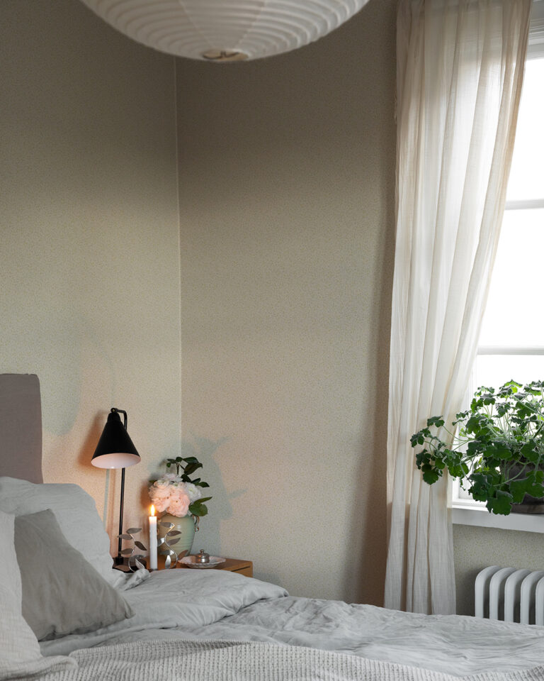 Light-colored, small-flowered wallpaper in a bedroom with a gray bed