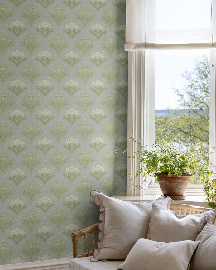 Ljusblå tapet med blommor i ett vardagsrum med en soffa