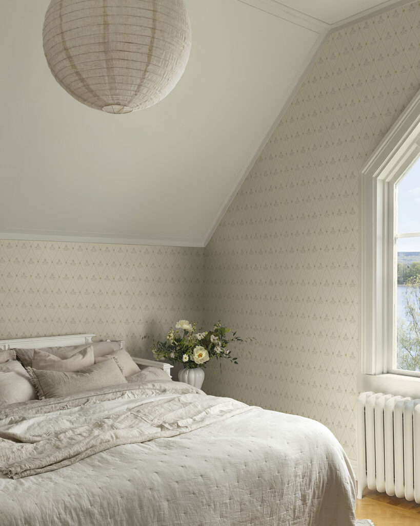 Cremevit tapet med trellismönster i ett sovrum med en blomvas