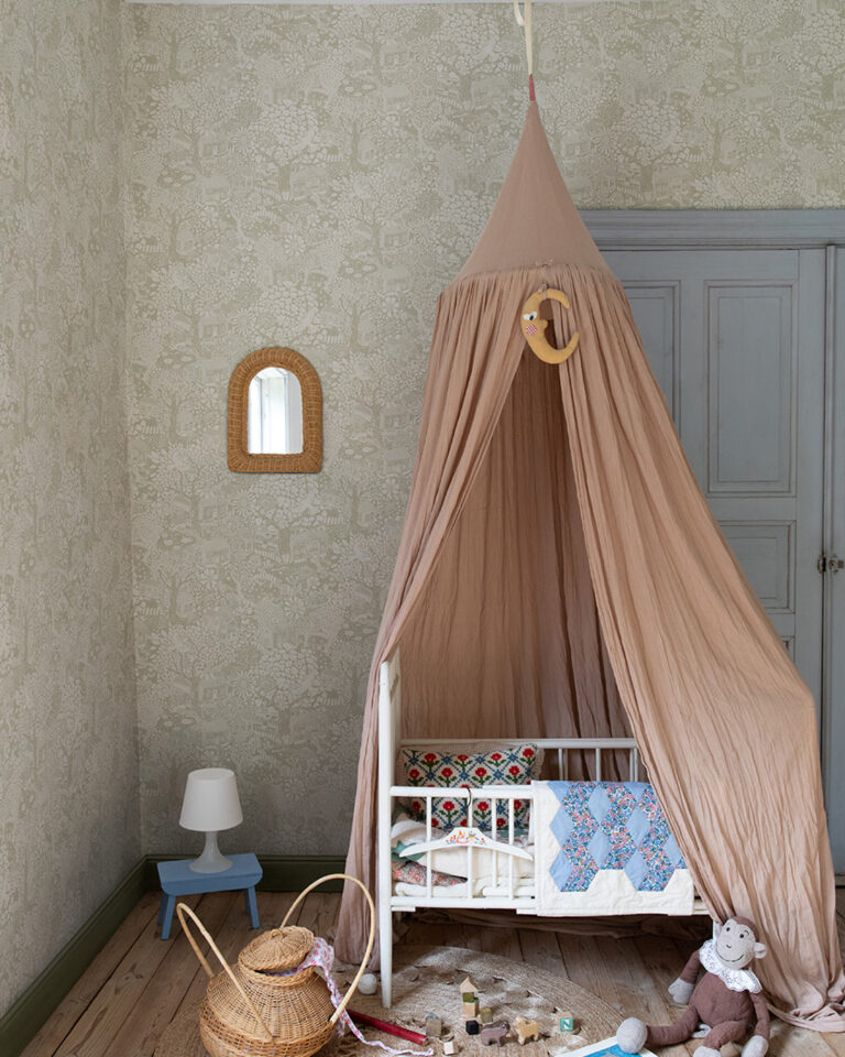 Wallpaper with a greige background featuring plants, houses, and animals in a child's room with a small bed