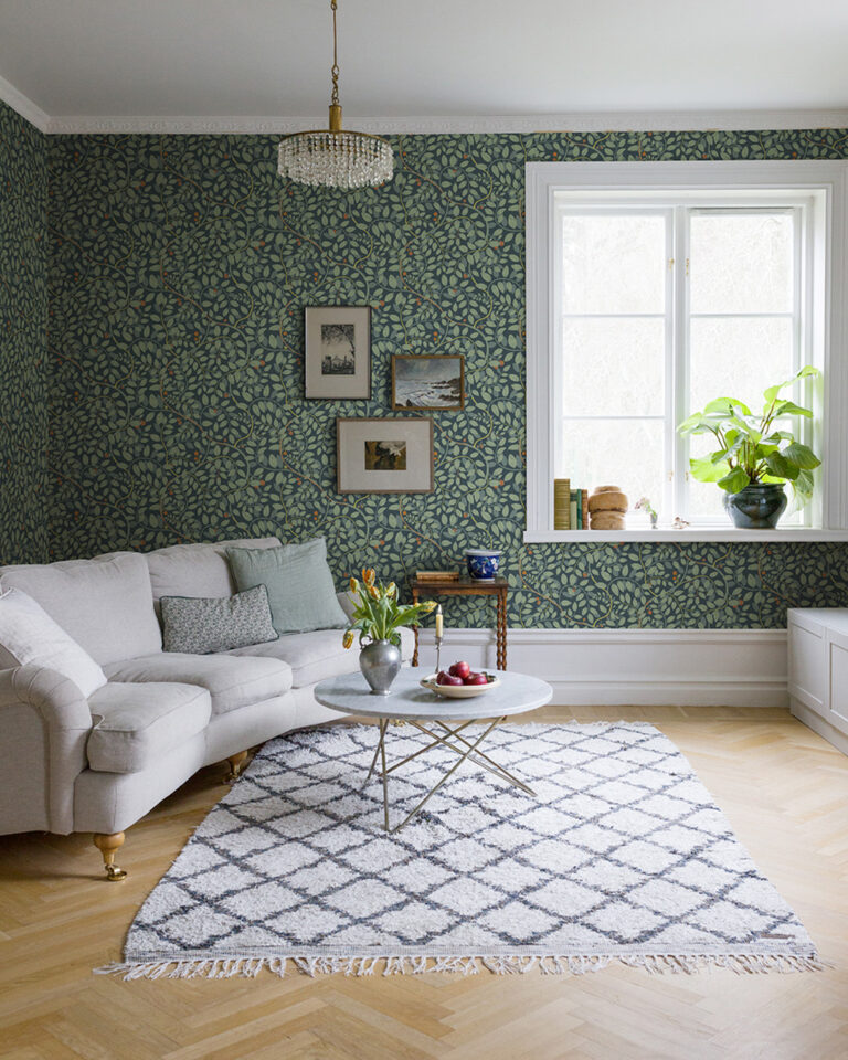 Grön tapet med ett slingrande bladverk i ett vardagsrum med en vit soffa
