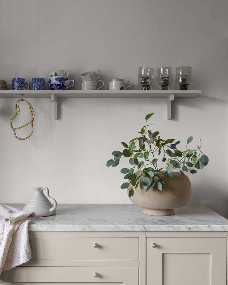 White wallpaper in a kitchen behind a counter with a marble top