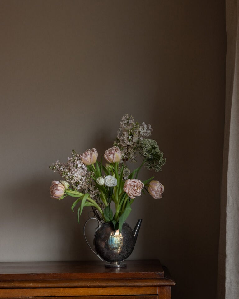 enfärgad brun tapet med mörkträmöbel framför med blommor i vas