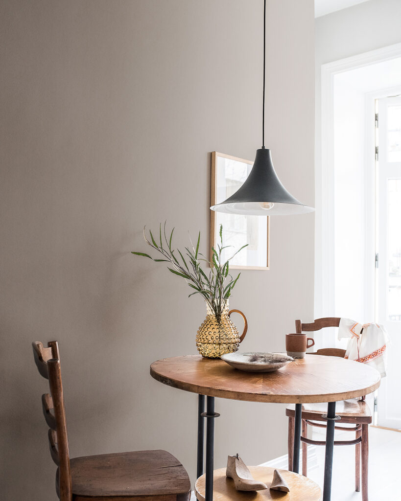 Brown wallpaper in a kitchen with chairs and a round table made of dark wood
