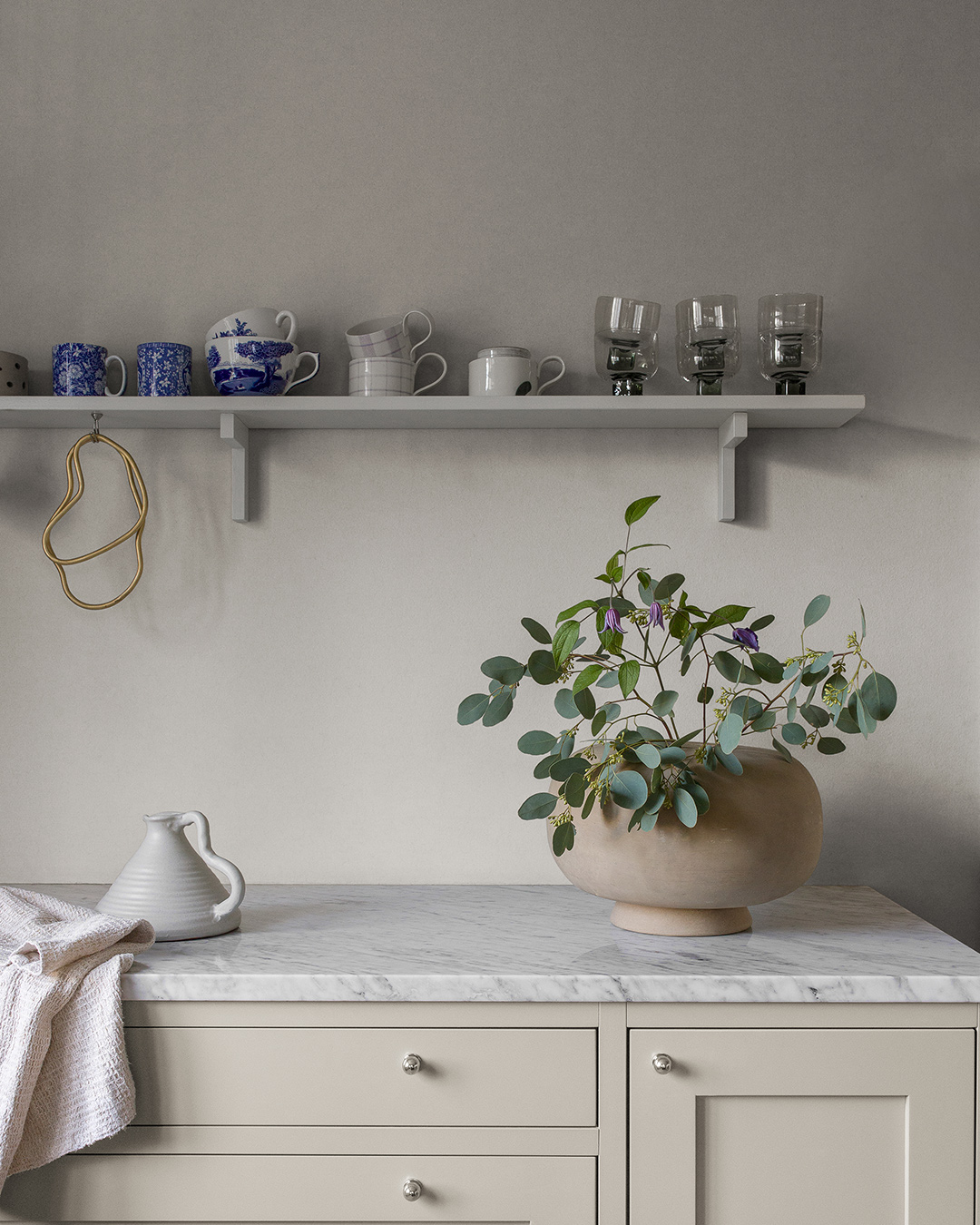 Gray wallpaper behind a kitchen countertop with marble and a white shelf