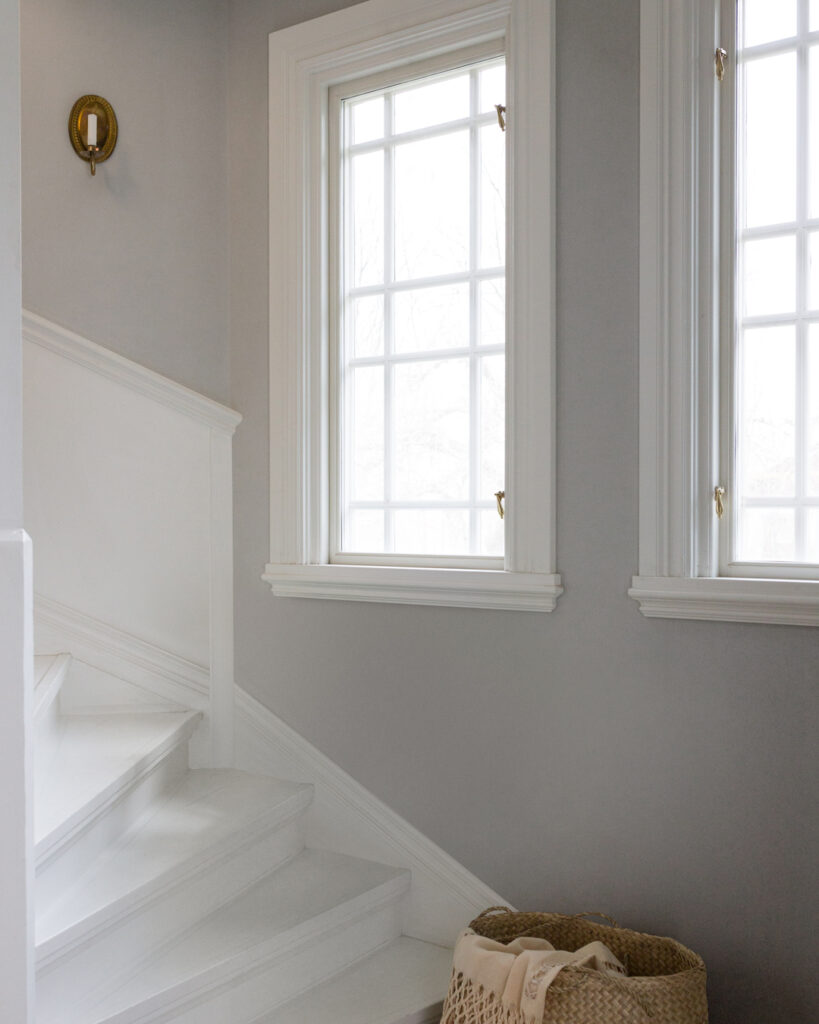 Gray wallpaper behind a white staircase and white windows