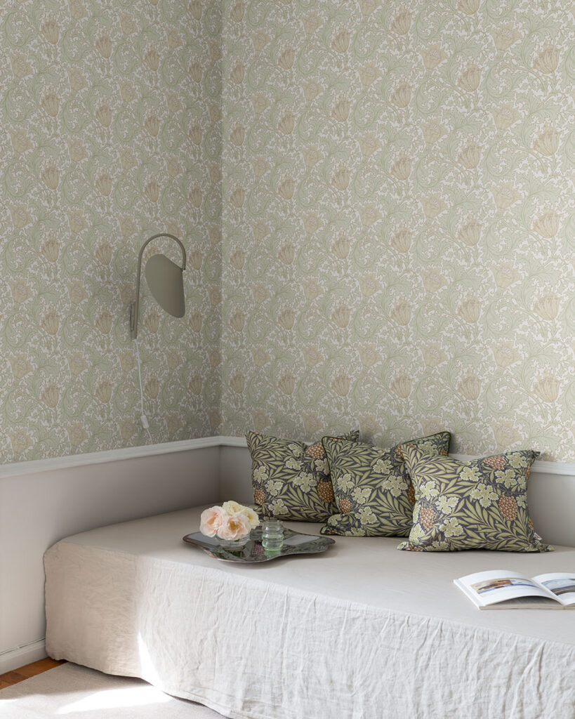 Blommig william morris tapet med varmvit botten och blommor i en mjuk beige ton i ett vardagsrum med prydnadskuddar på en soffa
