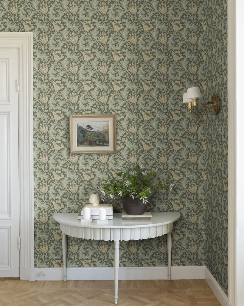 Green William Morris wallpaper with flowers (anemones) in a room with white trim and moldings.
