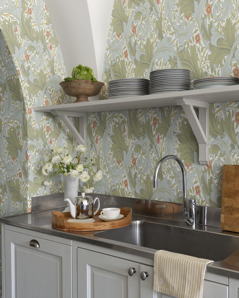 Grönt och blått tapetserat kök med bänk i rostfritt stål och öppna hyllplan. Tapet design: William Morris