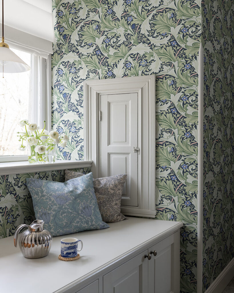 Wallpaper with a dark blue background and green leaves in a hallway with built-in storage and a white bench