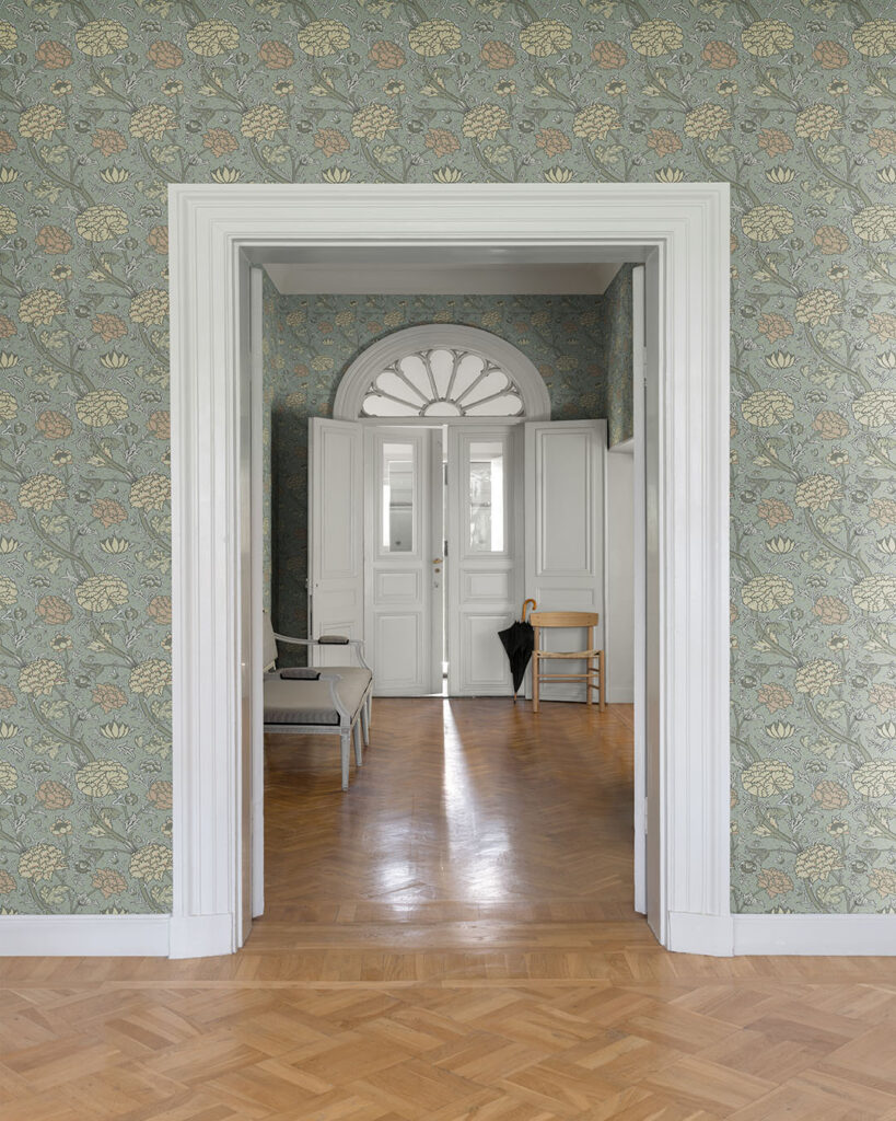 Wallpaper with a gray-blue background and peonies in beige and pink in an open hallway with white floors and door moldings