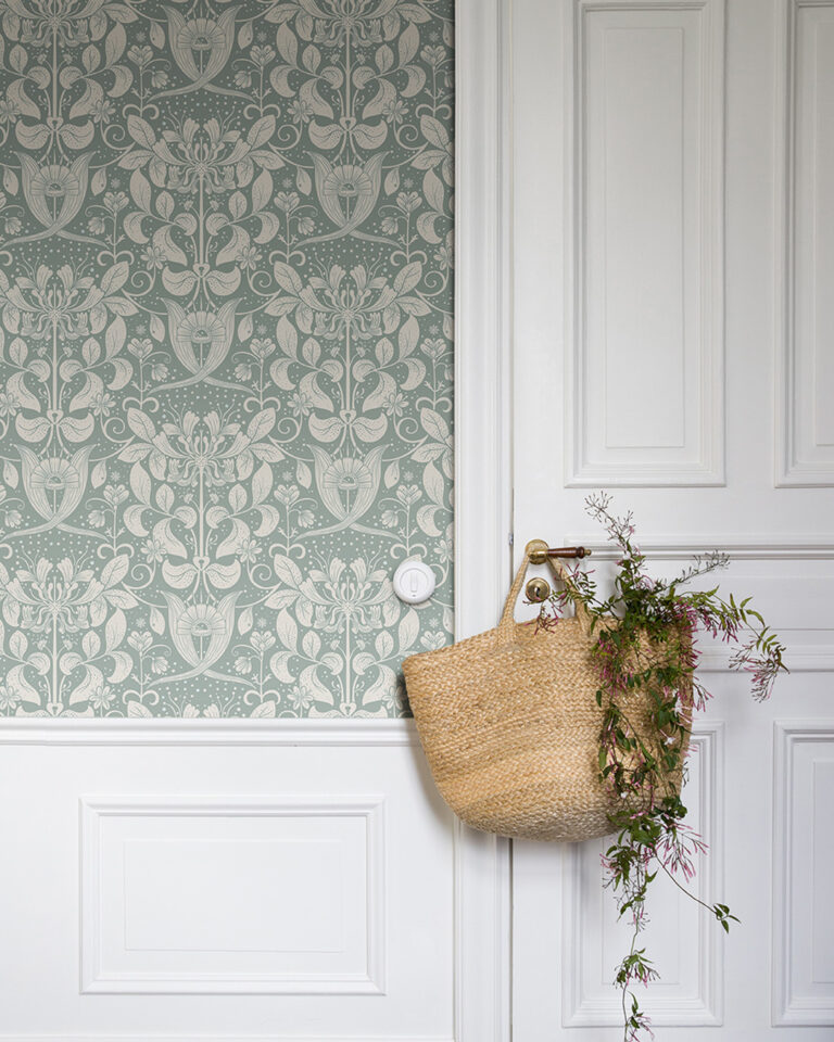 Light blue medallion wallpaper in a turn-of-the-century-style room with white wainscoting.