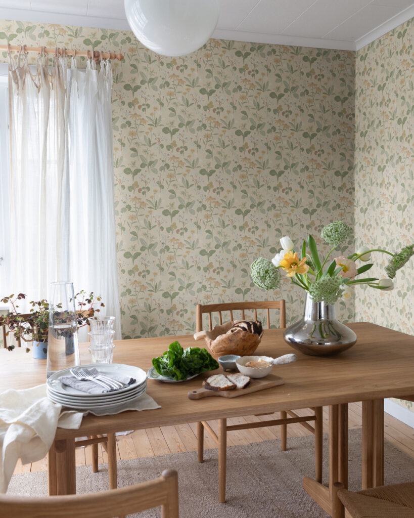 Light yellow floral wallpaper in a dining room with a large, set wooden table
