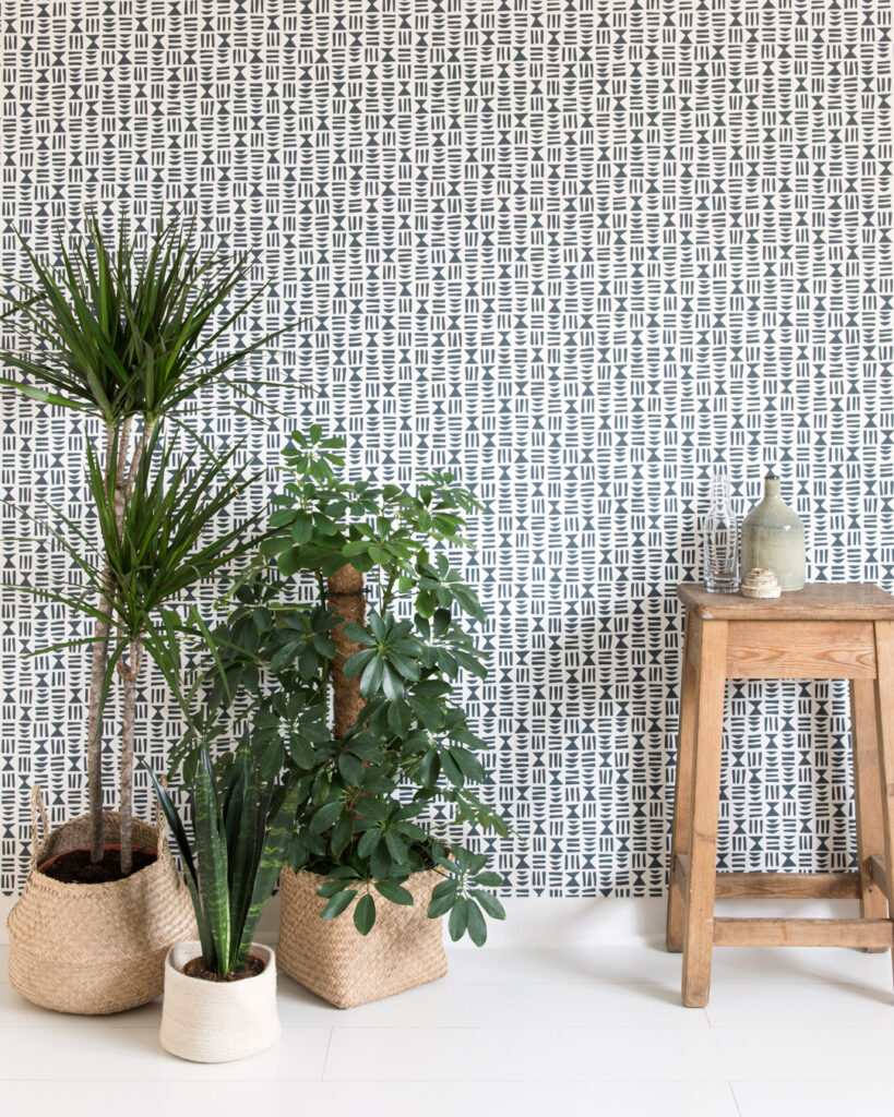 Black-and-white geometric retro wallpaper with a small pattern and green plants typical of the retro style