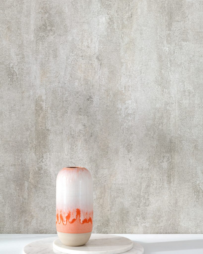 Gray concrete wallpaper behind a white bench with an orange vase