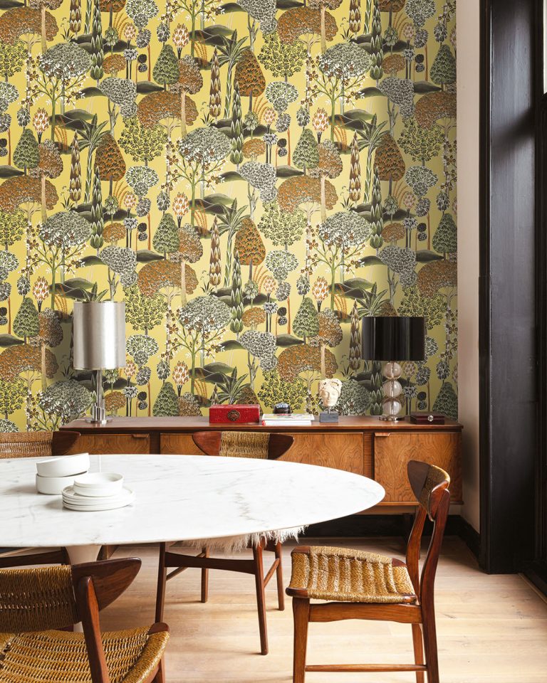 Light yellow wallpaper featuring trees in a dining room with a marble table and a wooden dresser
