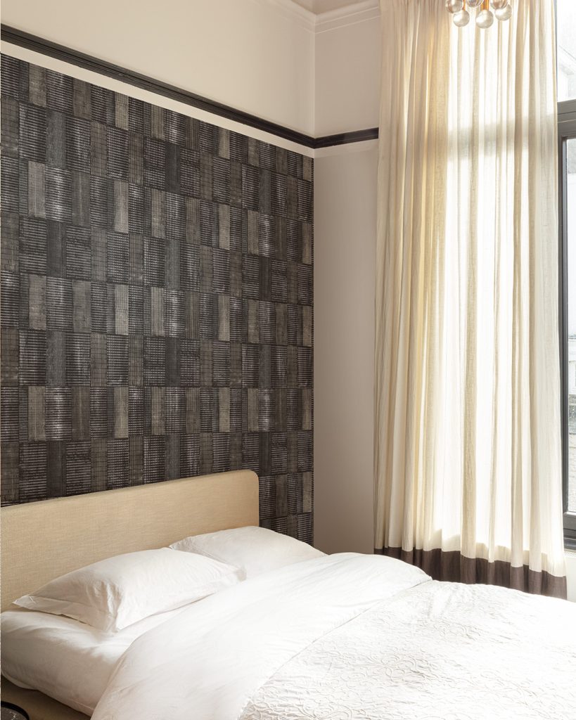 Wallpaper featuring geometric blocks with small stripes in shades of gray in a bedroom