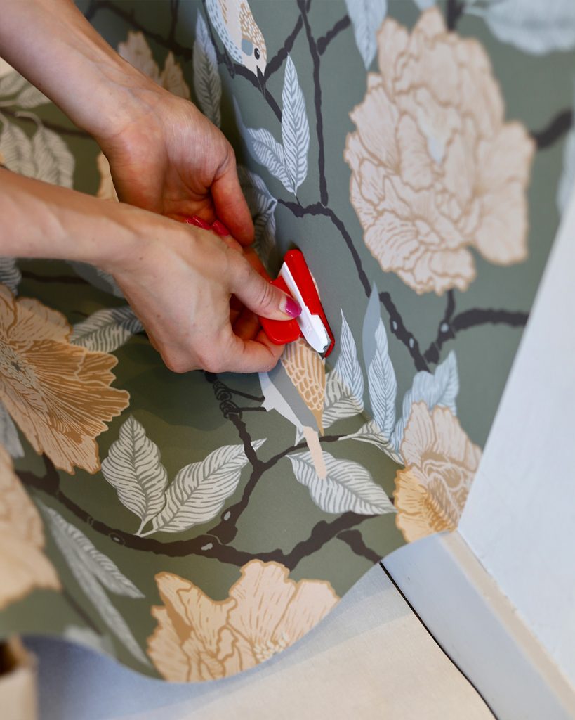 Hang wallpaper and trim it with a razor blade at the baseboard